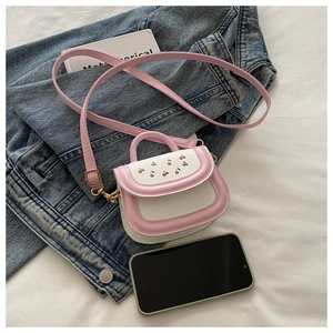 Mini crossbody bag with cherry pattern and pink strap next to a mobile phone for scale