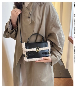 Detail of faux shearling trim on black leather crossbody bag with golden metal twist lock