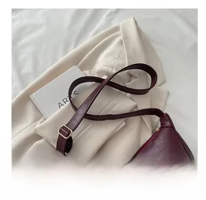 Detail der weinroten Handtasche aus Leder mit Narbenstruktur und goldener Metallschnalle