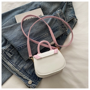 Detailed top view of white saddle mini bag with pink handles on denim and art book