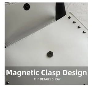 Detail view of magnetic closure and square stud rivets on white envelope bag