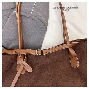 Detail of vintage brown corduroy tote bag showing the adjustable strap and metal buckle