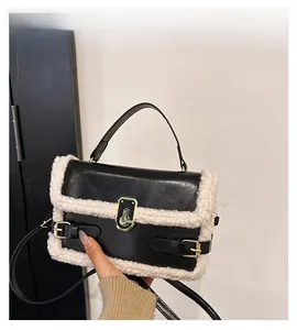 Detail of black leather handbag featuring white faux fur trim and gold metal swivel lock