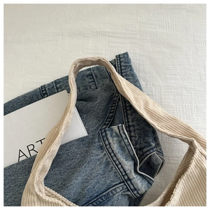 Détail de la bandoulière en velours côtelé beige et du tissu denim bleu foncé du sac
