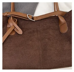 Detail of dark brown corduroy tote with leather handle and silver metal buckle