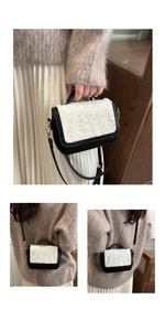 Close-up of contrast wool saddle bag with black leather and golden buckle details