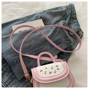Detail of mini pink cherry print crossbody bag with gold hardware on denim background