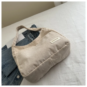 Détail du sac cabas en velours côtelé blanc cassé montrant la texture et l'écusson