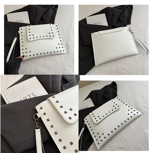 Detail view of white envelope clutch with metal studs and detachable wrist strap on artsy decor