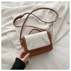 Detail of a brown faux leather crossbody bag with white sherpa flap and gold hardware
