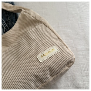 Détail de la texture en velours côtelé blanc cassé et de l'étiquette dorée tendance
