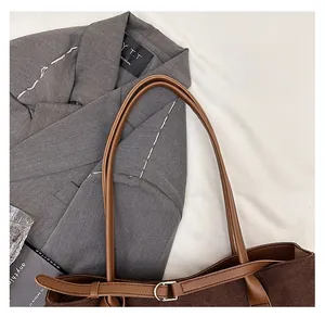 Detail of dark brown suede tote bag with leather strap and metal adjustment buckle