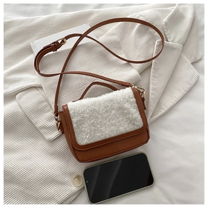 Detail of a brown leather and white faux fur saddle bag with golden hardware