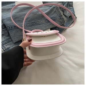Close-up of pink and white cherry mini crossbody bag held against a denim background