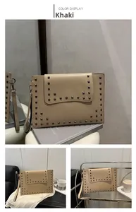 Detailed macro view of khaki envelope clutch bag with square metallic rivets and wrist strap