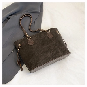 Detail of dark brown tote bag with matte texture and bronze metal ring buckle accents