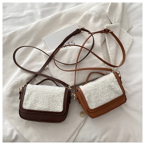 Detail of coffee and brown faux leather saddle bags with white shearling trim and gold hardware