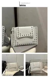 Detail of white leather handbag with black square studs and detachable wristlet strap