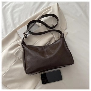 Top view of dark brown pebbled leather handbag with phone inside to show storage capacity