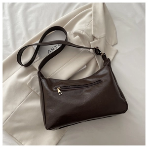 Detail view of dark brown PU leather bag with back zipper pocket on artistic white fabric
