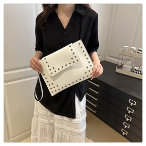 Lifestyle shot of a white matte leather clutch bag with dark grey square rivet details