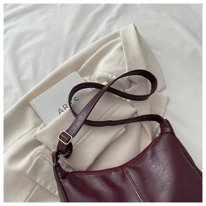 Close-up of wine red vintage PU leather bag with adjustable golden buckle and fine texture