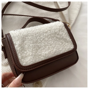 Detail of retro saddle bag showing brown leather texture and white lamb wool stitching