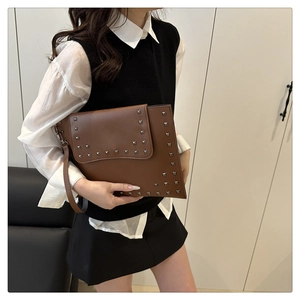 Close-up of vintage brown leather clutch bag with silver square metal studs for women