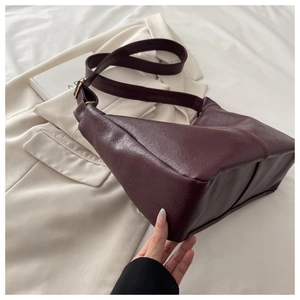 Detail of burgundy PU leather tote bag with pleat texture and adjustable shoulder strap