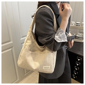 Détail du sac cabas en velours côtelé beige montrant la texture côtelée et l'étiquette mode