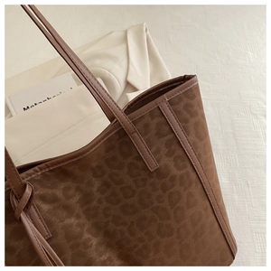 Detail of leopard print suede tote bag with knotted brown handles and fine stitching