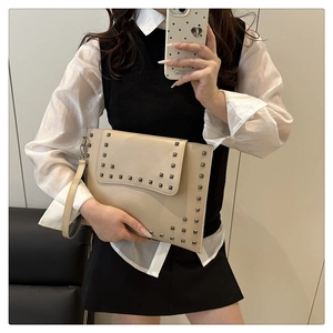 Chic beige envelope clutch bag with rivet accents and wristlet shown in a mirror selfie