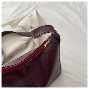 Close-up of deep wine red litchi texture PU leather bag with golden metal zipper detail