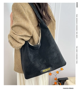 Close-up of black matte tote bag featuring yellow JACQEUE logo embroidery and suede texture