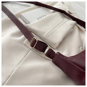 Close-up of burgundy PU leather shoulder bag with vintage texture and gold metal buckle