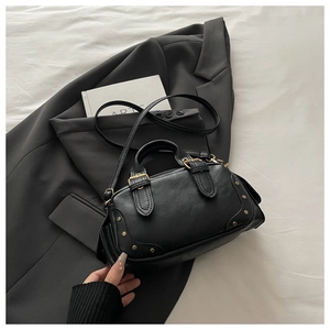 Close-up of black retro bowling bag with litchi texture and gold rivet details