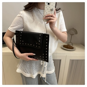 Close-up of black envelope clutch with silver square studs and metal chain strap