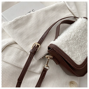 Detail of faux shearling and brown leather patchwork bag with gold metal buckle