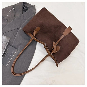 Detailed texture of dark brown corduroy tote bag with decorative leather buckle strap