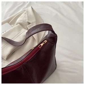 Detailed close-up of burgundy PU leather texture and gold zipper on a chic tote bag