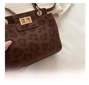 Detail of warm brown leopard print texture and golden metal twist lock on the handbag