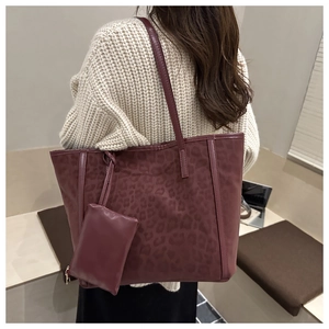 Detail of burgundy leopard embossed tote bag set shown on a model in beige knitwear