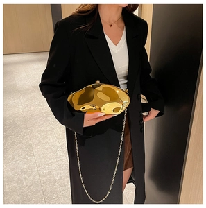 Close-up of golden irregular wave evening bag with a metallic mirror finish and chain