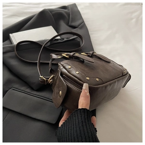 Detail of dark brown vintage bowling bag with gold rivets and wrinkled leather texture