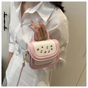 Detail of a pink and white cherry print handbag with gold buckle and top handle strap