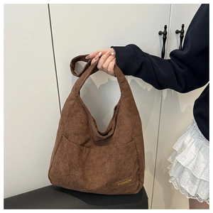 Gros plan du sac cabas en velours côtelé marron montrant la texture et l'étiquette