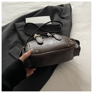 Detail view of vintage brown bowling bag featuring gold studs and premium textured leather