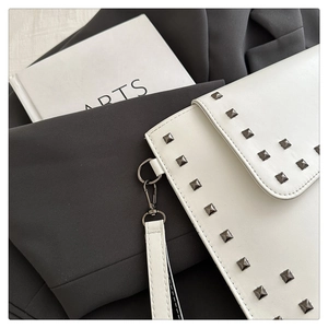 Detail of white leather envelope clutch with grey metal studs and detachable wrist strap