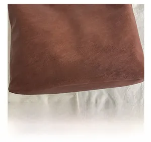 Close-up of brown textured leather tote bag with JACQEUE oval patch logo detail