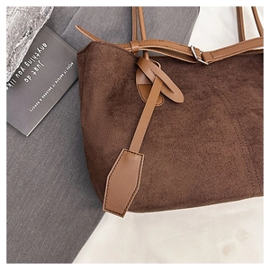 Detail of dark brown corduroy tote bag with synthetic leather strap and metal buckle